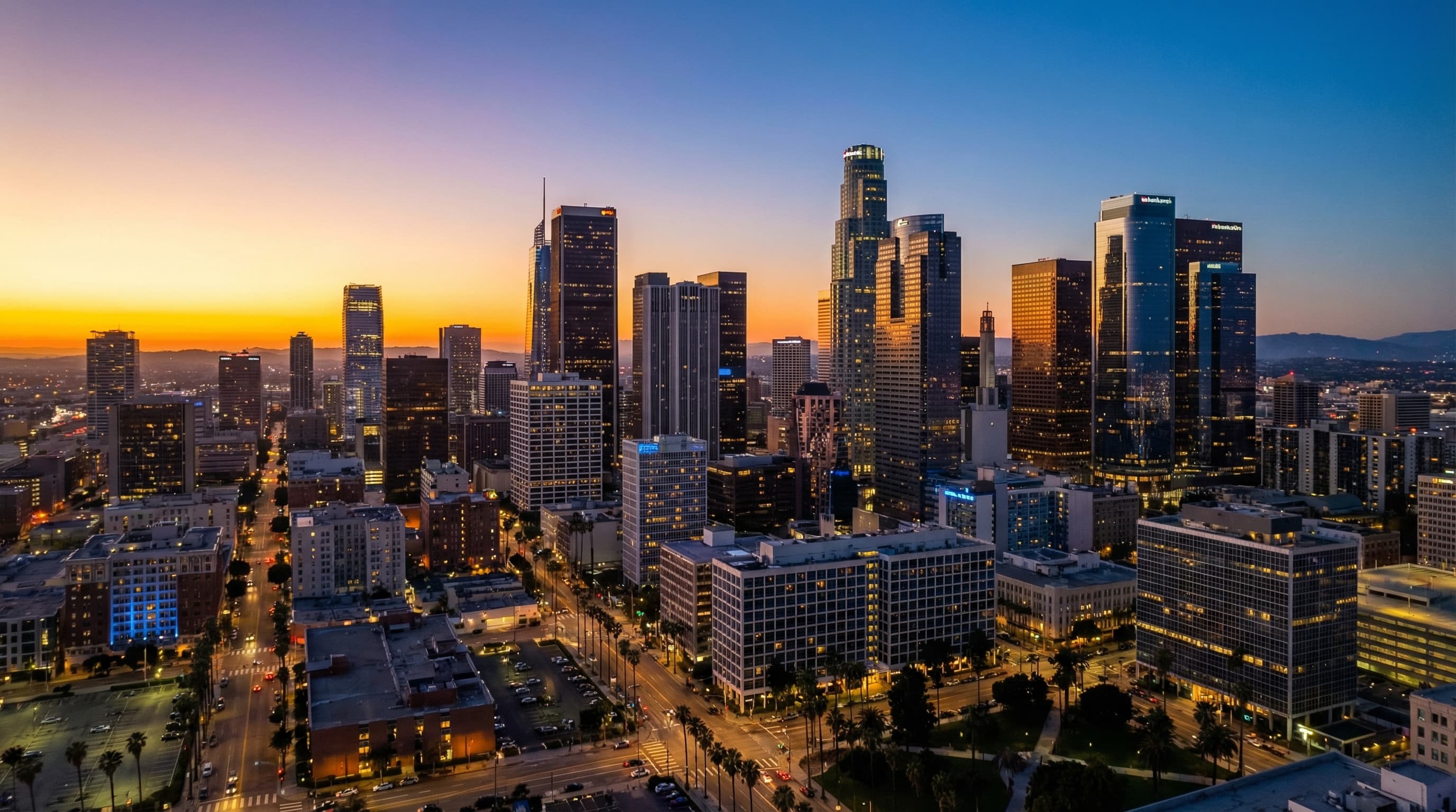 Stunning aerial view of downtown Los Angeles skyline at golden hour with palm trees and warm city lights